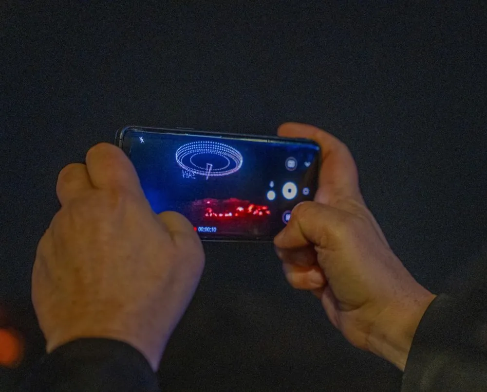 Hands filming the Matera 2026 drone show on a phone